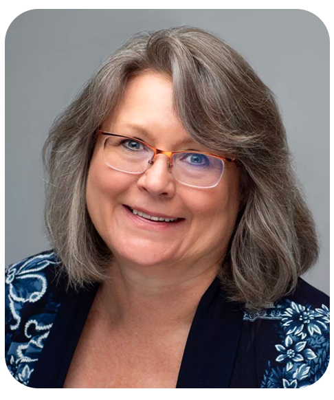 A head shot of Dawn Simpson. She is wearing a floral blouse and smiling.