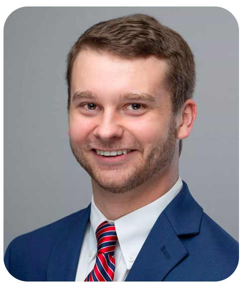 A head shot of Jeremy Bush wearing a suit and tie. He is smiling and looking into the camera.