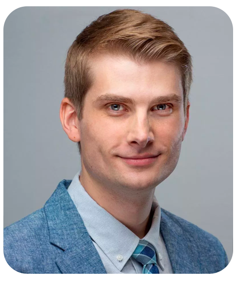 A head shot of Michael James. He is wearing a suit and tie and smiling.