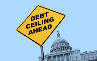 A large yellow traffic sign that reads "DEBT CEILING AHEAD" in bold black letters appears in front of the U.S. Capitol Building.